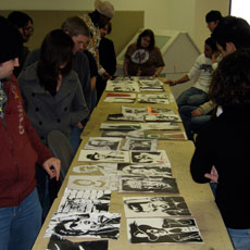 Students standing around a table of art work during critique.